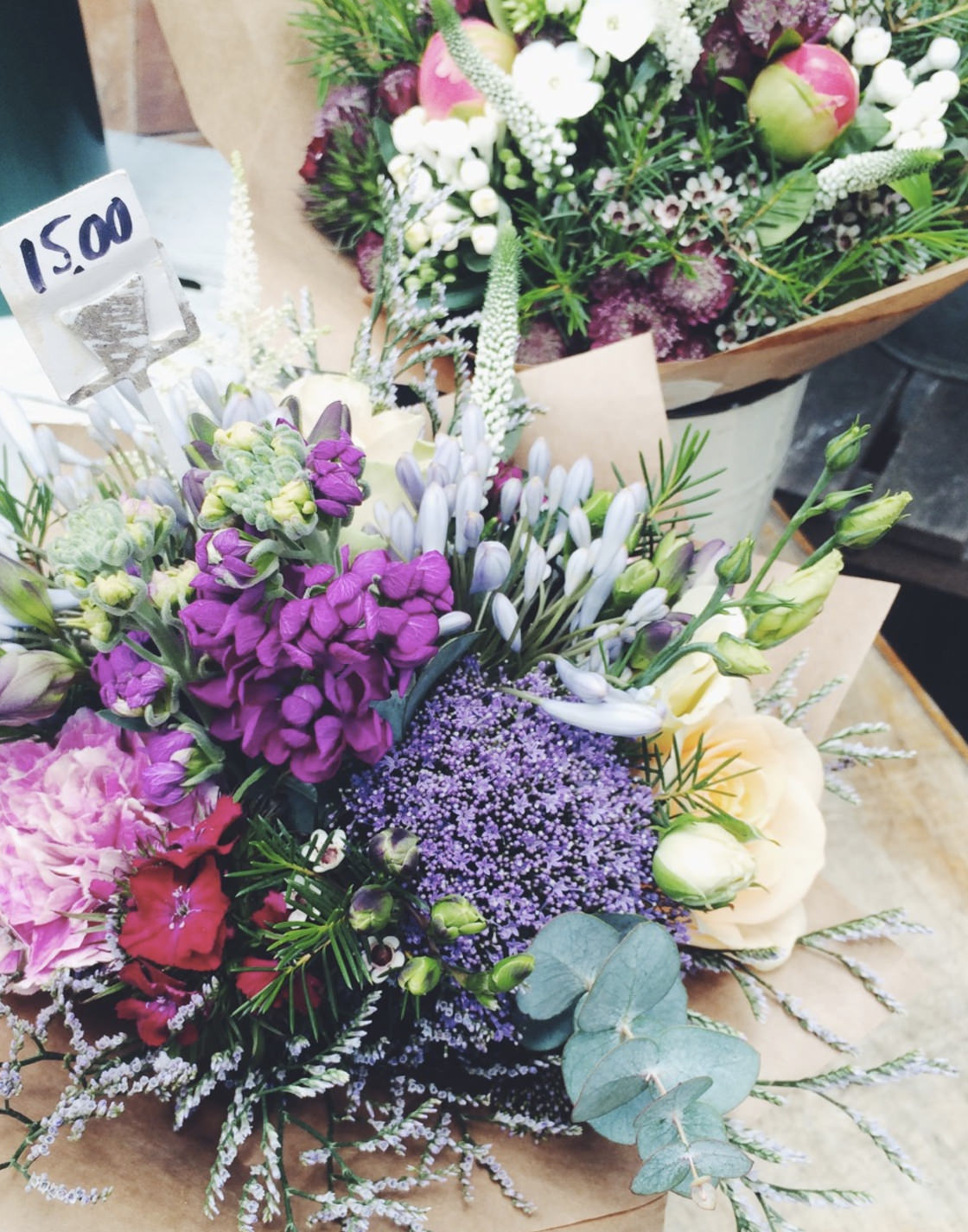 A boquet of flowers wrapped in brown paper